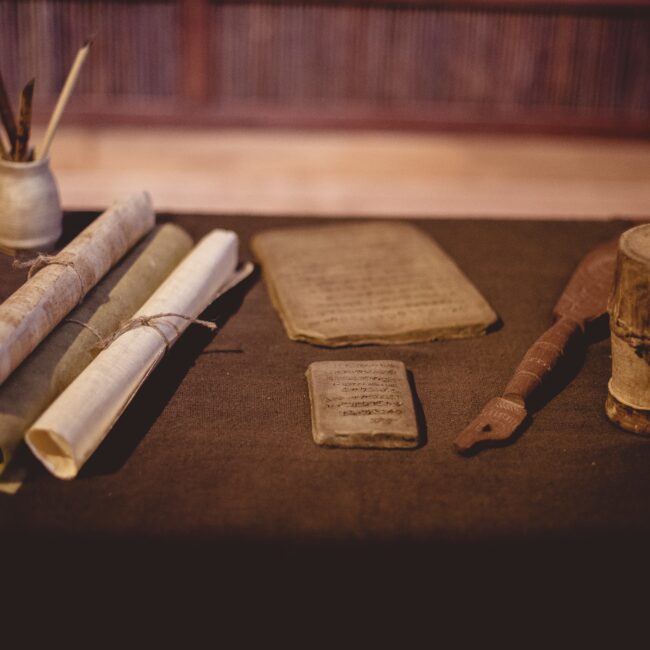 A closeup of parchment rolls with ancient tools on the table under the lights